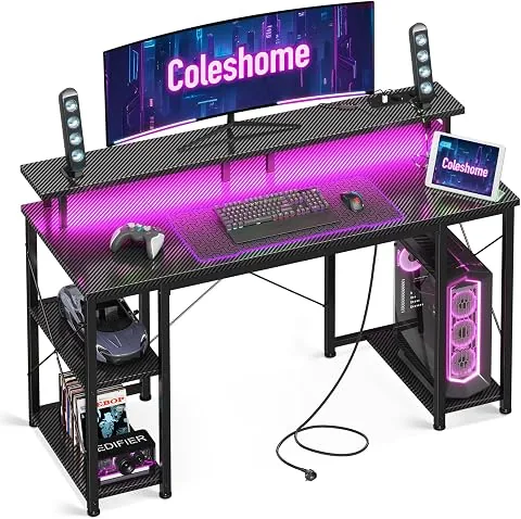 Coleshome Escritorio Gaming con LED, 120x50cm, Fibra de Carbono Negra | Iluminación LED, 2 Enchufes y 2 USB, Estantería Re